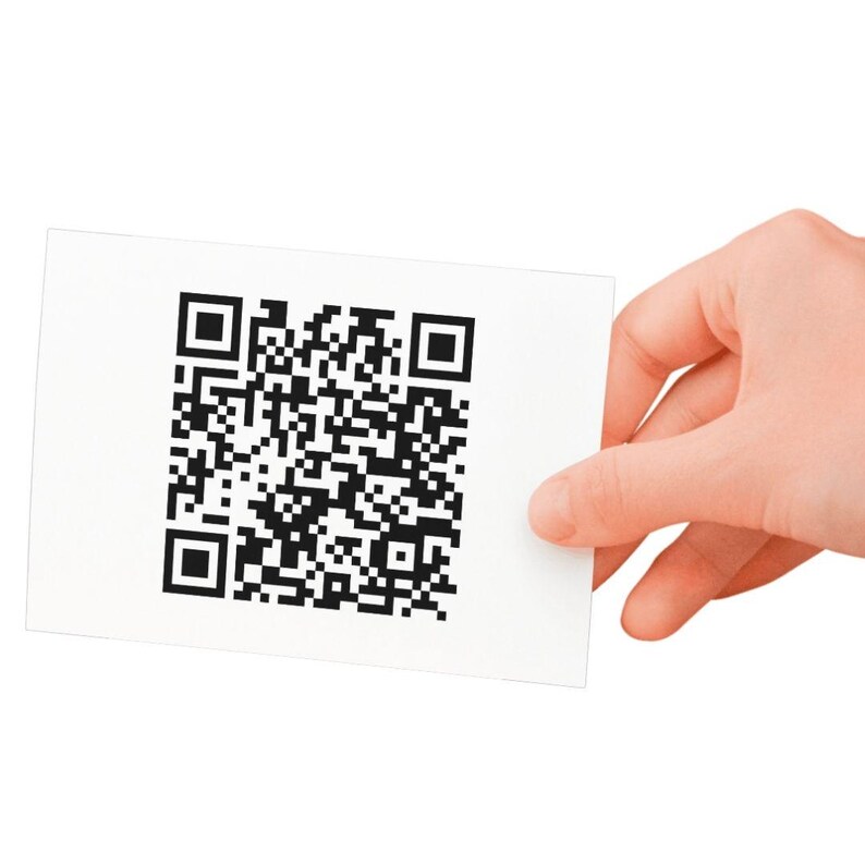 May include: A white card with a black and white QR code printed on it. The card is being held by a hand.