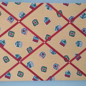 May include: A beige cork board with red ribbon crisscrossing the surface. The board is covered in a repeating pattern of colorful patches with the text "World Explorer" and "Adventure" printed on them.