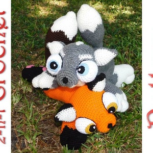 May include: A crochet pattern for a gray and white fox and an orange fox with black accents. The foxes are lying on their sides with their heads facing each other.