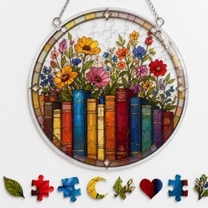 K&ouml;nnte beinhalten: Ein rundes Buntglasfenster mit einem farbenfrohen Blumenarrangement &uuml;ber einer Reihe von B&uuml;chern. Das Fenster ist von einem Puzzleteil-Design umrandet und h&auml;ngt an einer Kette. Mehrere Puzzleteile sind darunter verstreut.
