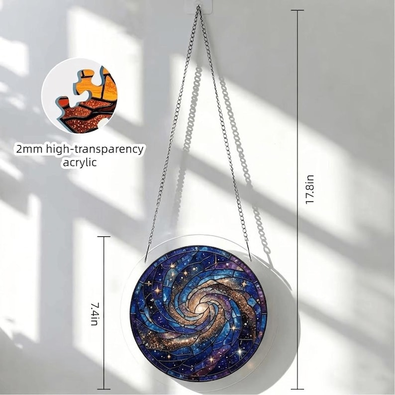 K&ouml;nnte beinhalten: Ein runder Galaxy-Suncatcher mit einem Durchmesser von 18,8 cm und einer L&auml;nge von 45,2 cm mit Kette. Das Design zeigt eine wirbelnde Galaxie in Blau-, Lila- und Goldt&ouml;nen. Der Text "2mm high-transparency acrylic" ist sichtbar.