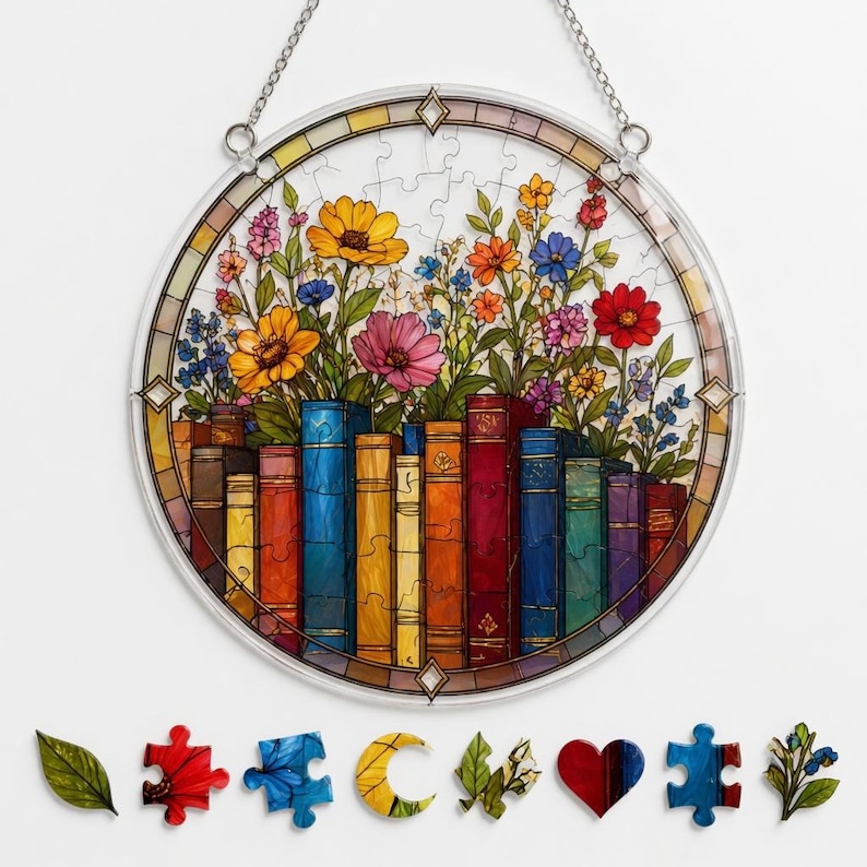 K&ouml;nnte beinhalten: Ein rundes Buntglasfenster mit einem farbenfrohen Blumenarrangement &uuml;ber einer Reihe von B&uuml;chern. Das Fenster ist von einem Puzzleteil-Design umrandet und h&auml;ngt an einer Kette. Mehrere Puzzleteile sind darunter verstreut.