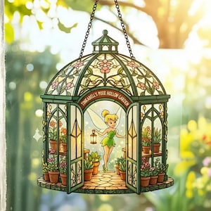 May include: A decorative stained glass garden scene with a fairy holding a lantern. The green and pink glass structure features the text "Tinkerbell's Pixie Hollow Garden" and is filled with potted plants. It hangs from a chain.