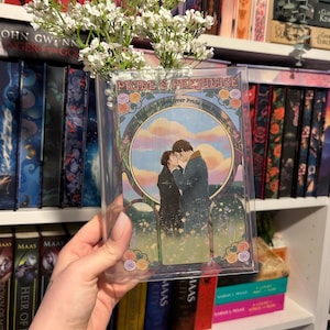 May include: A clear plastic cover with a colorful illustration of a couple embracing in a field of flowers. The text "Pride & Prejudice" is printed on the cover.