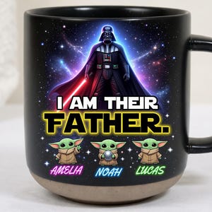 May include: Black ceramic mug featuring Darth Vader with a red lightsaber against a starry background. The text "I AM THEIR FATHER" is displayed, along with three Grogu characters and the names Amelia, Noah, and Lucas.