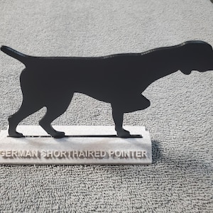 Puede incluir: Silueta negra de un Braco Alemán de Pelo Corto sobre una base blanca con el texto "GERMAN SHORTHAIRED POINTER".