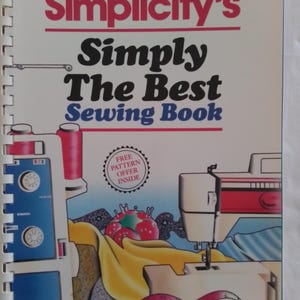Può includere: Un libro intitolato "Simplicity's Simply The Best Sewing Book" con un'illustrazione colorata di una macchina da cucire, tessuto e filo. La copertina del libro include anche un timbro che dice "Offerta di modello gratuito all'interno".