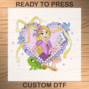 May include: A purple heart-shaped design with a yellow ribbon bow, featuring a cartoon image of Rapunzel from the Disney movie Tangled. She is holding a book with a blue bird on it. There is a green chameleon, a crown, and a hairbrush in the design. The text "CUSTOM DTF" is at the bottom of the design.