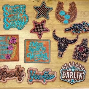 May include: A collection of embroidered patches featuring western-themed designs including a skull in a cowboy hat, a raccoon with a lasso, a bull skull, a horseshoe, stars, a bow, and text phrases like "Sweet and Sassy," "Howdy," and "Yee Haw."