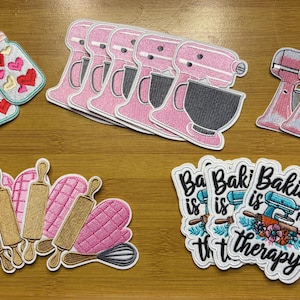 May include: Embroidered patches featuring baking-themed designs. Includes pink stand mixers, jars with hearts, rolling pins, oven mitts, and patches with the text "Baking is my therapy".