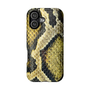Peut inclure: Une coque de téléphone avec un motif peau de serpent. La coque présente un motif répété d'écailles jaunes, marron et noires. La coque a une découpe pour l'appareil photo avec deux lentilles.