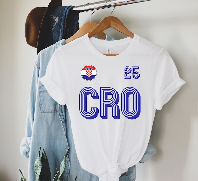 May include: White t-shirt with a blue and red Croatian flag, the word "CRO" in blue, and the number "25" in blue.
