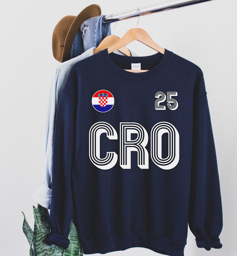 May include: A navy blue sweatshirt with a white outline of the word "CRO" and the number "25" printed on the front. A small circle with the Croatian flag is also printed on the front.