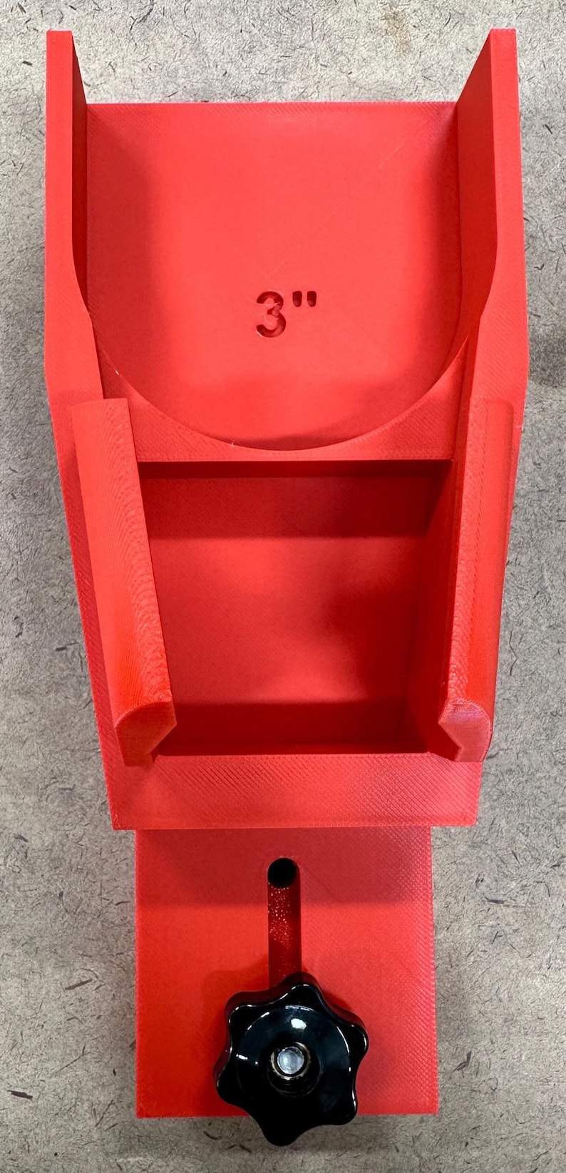May include: A bright red, 3D-printed adjustable bracket with a black knob. The bracket has a 3-inch marking and a slot for adjustment. The design includes a base, a central support, and side supports.