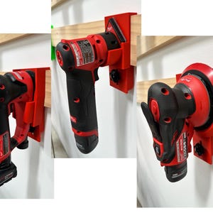 Puede incluir: Tres herramientas eléctricas rojas y negras montadas en una pared blanca. Cada herramienta está asegurada en un soporte rojo sujeto a una tabla de madera. Las herramientas incluyen una lijadora, un taladro y una multiherramienta oscilante.