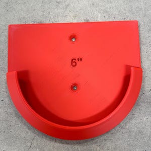 May include: A bright red, semi-circular shelf with a curved front and a flat back. The shelf has two pre-drilled holes and the number "6" with quotation marks printed on the surface. The shelf is approximately 6 inches wide.