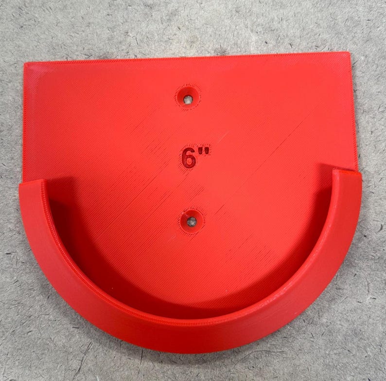 May include: A bright red, semi-circular shelf with a curved front and a flat back. The shelf has two pre-drilled holes and the number "6" with quotation marks printed on the surface. The shelf is approximately 6 inches wide.