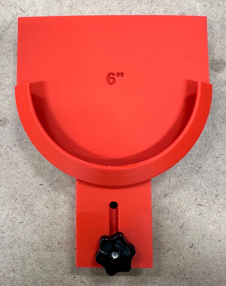 May include: A bright red tool with a 6-inch measurement marking. The tool features a curved section and a rectangular base with a black star-shaped knob. The tool is designed for a specific purpose.