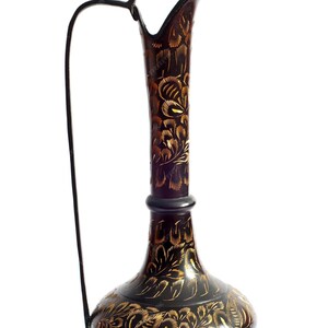 Könnte beinhalten: Eine dekorative Vase in Schwarz und Gold mit aufwendigen floralen Mustern. Die Vase hat einen hohen, schlanken Hals und einen breiten, runden Boden.