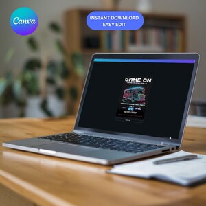 May include: A silver laptop displaying a digital invitation with the text "GAME ON" and a neon-style graphic of a food truck. The screen also shows "INSTANT DOWNLOAD EASY EDIT" and the Canva logo. A pen and notepad are on the wooden surface.
