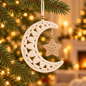 May include: A cream-colored crocheted crescent moon ornament featuring a textured stitch pattern, suspended by a matching cord with a gold bead. A smaller, light brown crocheted star hangs from the center of the moon by a cord.