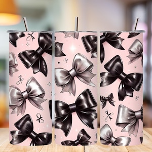 May include: A set of three stainless steel tumblers with lids and straws. Each tumbler features a repeating pattern of black and silver bows on a light pink background. The bows are detailed with shading and highlights.