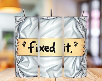 Könnte beinhalten: Ein weißer Becher mit einem Edelstahlstrohhalm. Der Becher hat ein hellgelbes Banner mit den schwarzen Worten "fixed it", mit Pfotenabdrücken auf jeder Seite. Der Hintergrund hat ein weißes, zerknittertes Papierdesign.