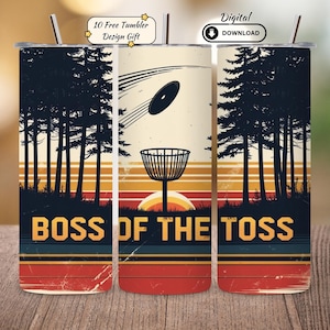 Op de afbeelding: Roestvrijstalen beker met een retro-ontwerp met een discgolfmand, schijf en bos-silhouet. De tekst "BOSS OF THE TOSS" wordt vet weergegeven. Inclusief een rietje en een "Digital Download"-pictogram.