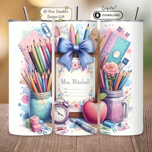 May include: A white tumbler featuring a watercolor design with school-themed elements. The design includes pencils, a ruler, a pink apple, and a blue bow. The tumbler has the text "Mrs. Mitchell" and "10 Free Tumbler Design Gift".
