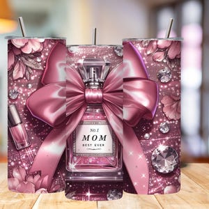 May include: A pink tumbler with a floral and glitter design, featuring a perfume bottle with a pink bow and the text "No. 1 MOM BEST EVER." Includes a nail polish bottle and diamond accents.