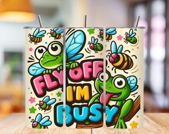 May include: A cylindrical tumbler with a cream background featuring a cartoon frog with blue wings and various flying insects. The text "FLY OFF I'M BUSY" is printed in large, colorful, bubble-style letters. The tumbler includes a metal straw.
