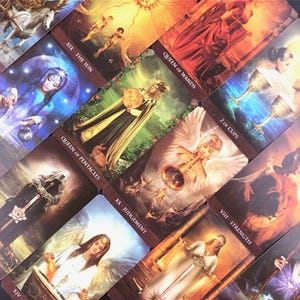 May include: A collection of tarot cards featuring various illustrations and titles. The cards display images of figures, angels, and symbols, including "The Sun," "Queen of Wands," and "2 of Cups." The color palette includes warm tones of gold, orange, and brown.