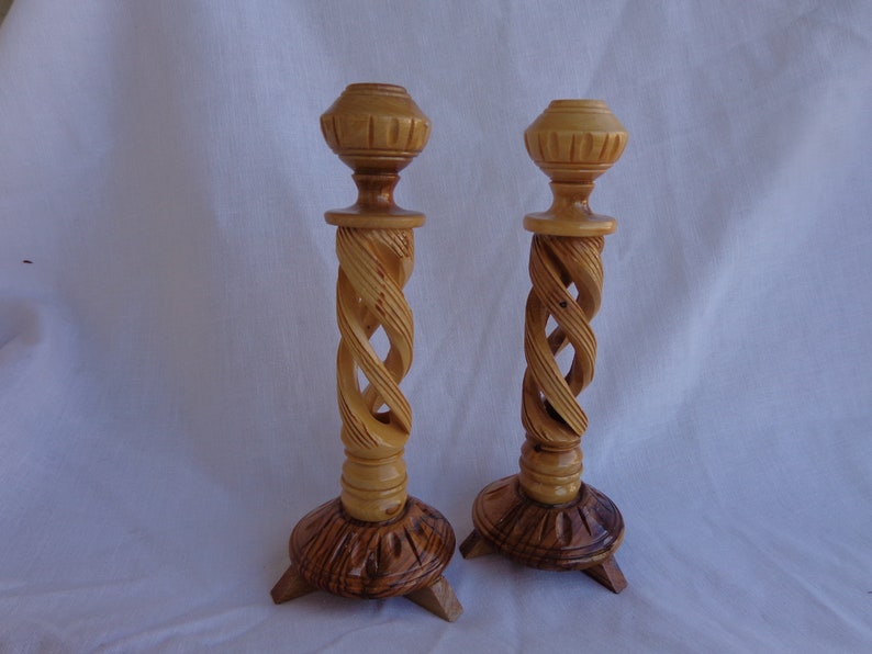 May include: A pair of wooden candle holders with a spiral design. The candle holders are made of light brown wood and have a natural finish.
