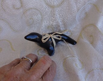 May include: A black ceramic penguin figurine with a small, tied, beige ribbon bow.