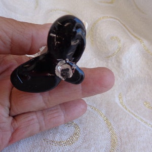 May include: A black plastic butterfly-shaped hair clip with a shiny silver accent.