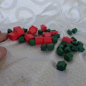 May include: A collection of red and green wooden houses, likely game pieces for a board game.