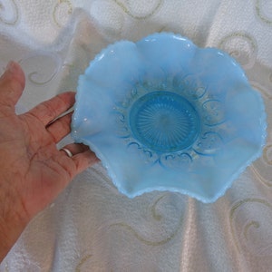 May include: A light blue glass bowl with a scalloped edge and a decorative pattern. The bowl is made of opalescent glass and has a frosted finish.