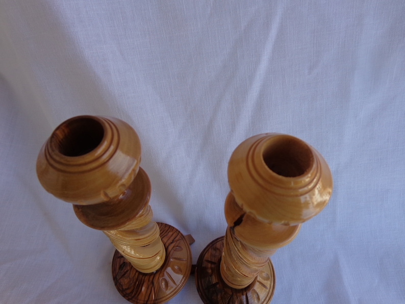 May include: A pair of wooden candle holders with a natural wood finish. The holders are intricately carved and have a unique, rustic look.