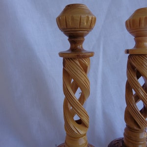 May include: Two wooden candle holders with a spiral design. The holders are made of light brown wood and have a simple, elegant design.