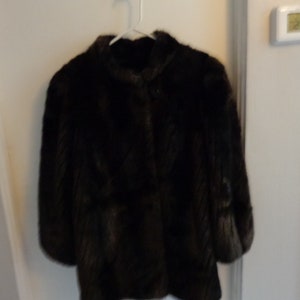 May include: A brown fur coat with a button closure.