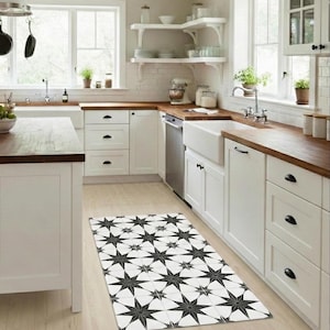 May include: A kitchen with white cabinets, wooden worktops, and a patterned rug. The rug features a repeating star design in black and white. The kitchen also includes a sink, dishwasher, and open shelving.