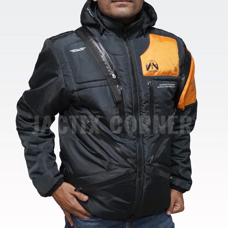 May include: Black hooded jacket with orange accents on the shoulder and chest. Features multiple zippered pockets and the text "TACTIX CORNER". The jacket has a diagonal zipper and a logo patch.