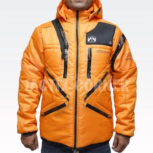 May include: Bright orange winter jacket with a hood and black accents. The jacket features multiple zippered pockets and a quilted design. Text on the jacket includes "SURVEILLANCE MARINE" and a logo. A stylish and functional outerwear piece.