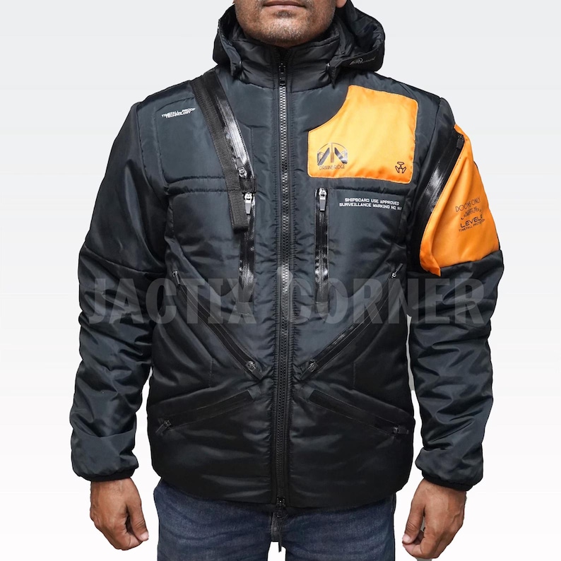 May include: Black and orange hooded jacket with multiple zippers and pockets. The jacket has a quilted design and features orange panels on the chest and upper arm. Text is printed on the jacket. A stylish and functional outerwear piece.