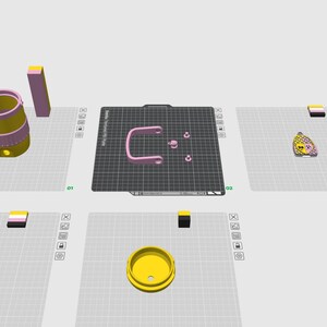 Op de afbeelding: Een digitale 3D-modelleringsinterface met diverse onderdelen, waaronder een gele cilindrische container, een roze U-vormige handgreep, twee kleine roze ronde onderdelen en twee hartvormige hangers met gele en roze patronen.