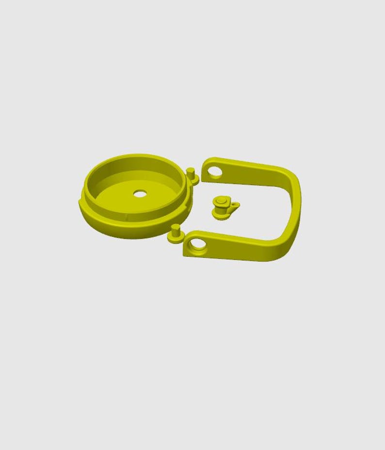 May include: A disassembled yellow plastic component set, featuring a circular base with a central hole, a U-shaped handle, and a small, separate piece. The parts are arranged against a light gray background.