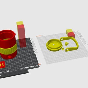 May include: A 3D-printed red and yellow tumbler with a handle and lid, along with a separate red and yellow block. The McDonald's logo is visible on a black surface. The tumbler is disassembled.