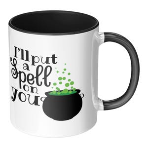 May include: White ceramic mug with a black interior and handle. The mug features the text "I'll put a spell on you" with a graphic of a black cauldron with green bubbles. A fun, spooky design.