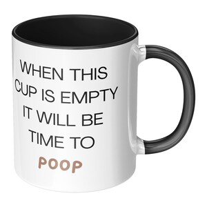 May include: White ceramic coffee mug with a black rim and handle. The mug has black text that reads "When this cup is empty it will be time to poop".