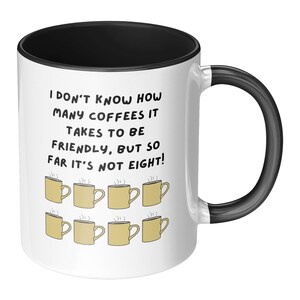 Peut inclure: Mug à café blanc avec intérieur et anse noirs. La tasse présente le texte "I DON'T KNOW HOW MANY COFFEES IT TAKES TO BE FRIENDLY, BUT SO FAR IT'S NOT EIGHT!" et des illustrations de tasses à café.
